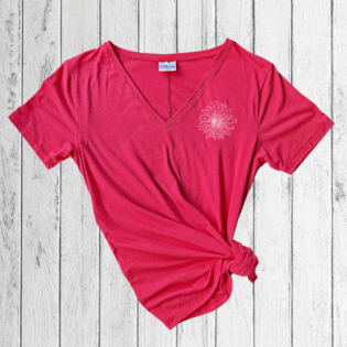 Pink t-shirt with floral design on wooden background.