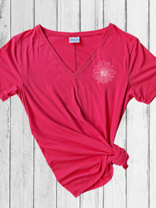 Pink t-shirt with floral design on wooden background.