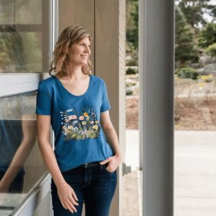 Smiling person wearing floral blue t-shirt outside.