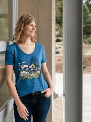 Smiling person wearing floral blue t-shirt outside.