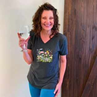Woman in floral shirt holding wine glass, smiling.